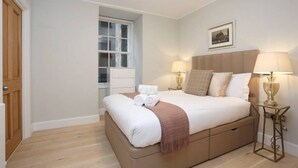 Un dormitorio con una cama grande, dos lámparas de noche, una ventana y una puerta.