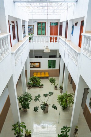 Un atrium à plusieurs niveaux, doté d’un espace central avec des sièges, des plantes en pot et un luminaire suspendu.