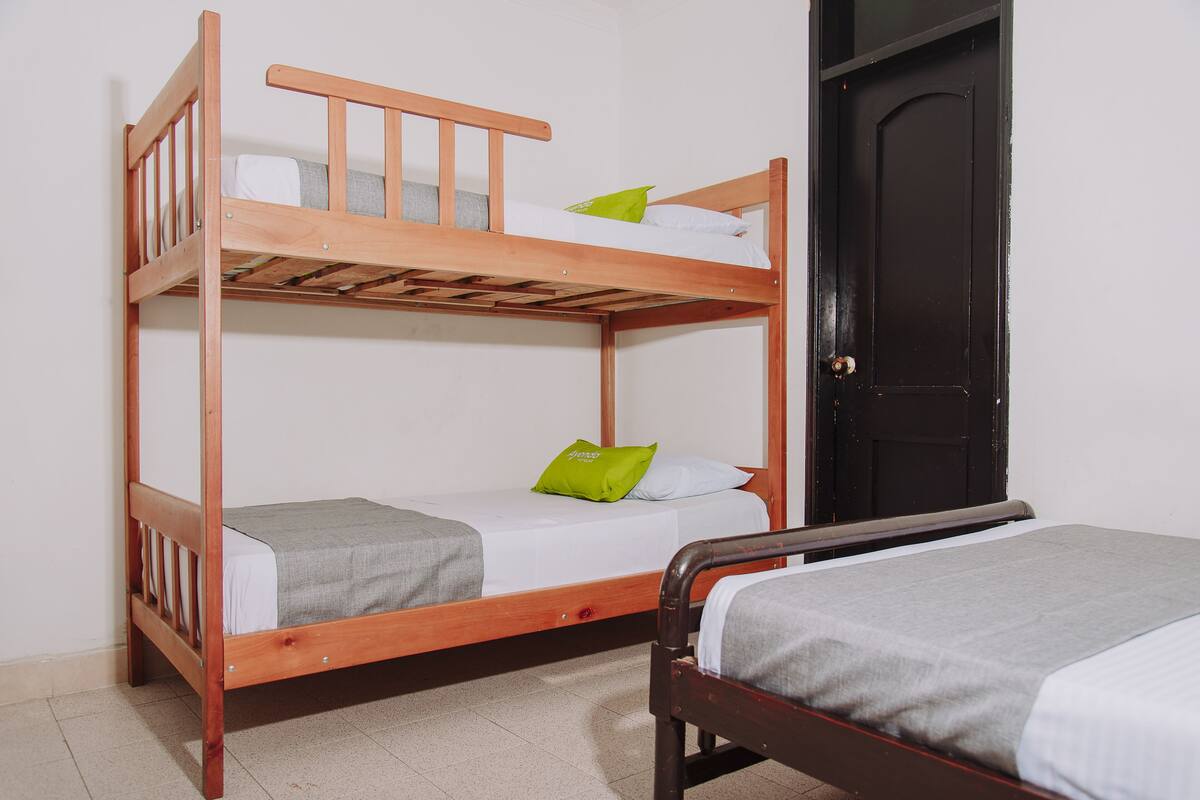 Ein Schlafraum mit Etagenbetten, einer Tür und einem Einzelbett.