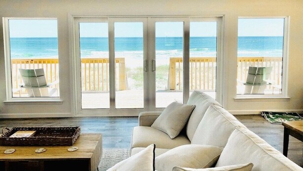 A spacious living area with a large window overlooking a beach. - Beach House - Gulf Front!  Right on the Beach! - WIFI - Sleeps 10- Pools (Gulf shores)