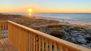 A wooden deck overlooking a beach with a sunset in the background. - Beach House - Gulf Front!  Right on the Beach! - WIFI - Sleeps 10- Pools (Gulf shores)