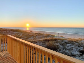 A wooden deck overlooking a beach with a sunset in the background. - Beach House - Gulf Front!  Right on the Beach! - WIFI - Sleeps 10- Pools (Gulf shores)