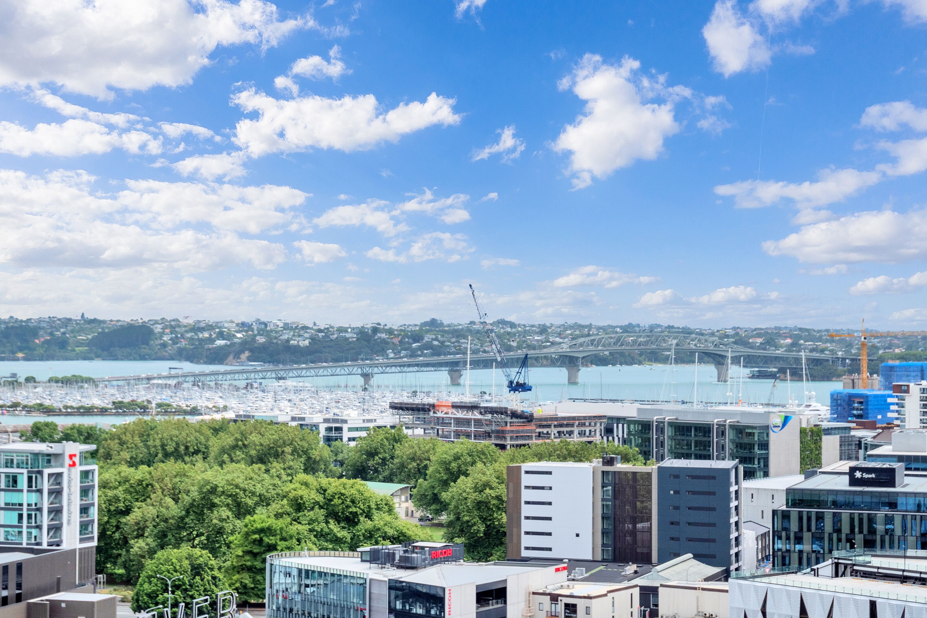 A cityscape with modern buildings, a bridge, and a marina.