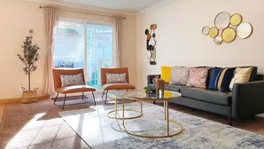 A living room with a sofa, two armchairs, a coffee table, and a decorative wall piece.