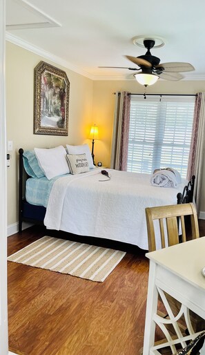 A neatly arranged bedroom with a bed, bedside lamp, ceiling fan, and a framed picture on the wall. - Southern Charm /Southern Hospitality! (Chesterfield)
