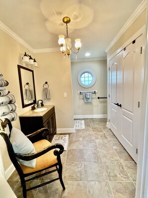 A bathroom with a vanity, a mirror, a chandelier, a towel rack, and a door. - Southern Charm /Southern Hospitality! (Chesterfield)