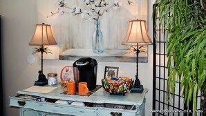 A rustic coffee table with a vintage aesthetic, featuring a coffee maker, orange mugs, a decorative bowl, and a framed picture. - Southern Charm /Southern Hospitality! (Chesterfield)