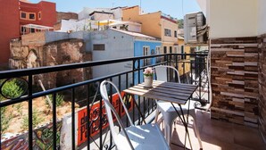 A balcony with a table and chairs, overlooking a street with colorful buildings. - STREET ART FANTASY 1 APARTMENT (MALAGA)