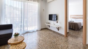 A modern hotel room with a large window, a flat-screen TV, a small wooden side table, and a bed with a headboard. - STREET ART FANTASY 1 APARTMENT (MALAGA)
