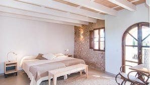 Ein Schlafzimmer mit einem Bett, Nachttischen, einer Bank, einem Stuhl und einem Fenster mit Blick.