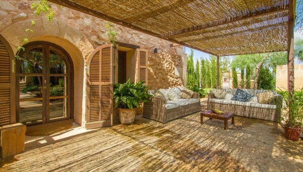 Relax in a secluded outdoor space with a stone wall, wicker sofas, and a wooden coffee table.