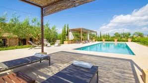 Ein Poolbereich mit Liegestühlen und einer Pergola.