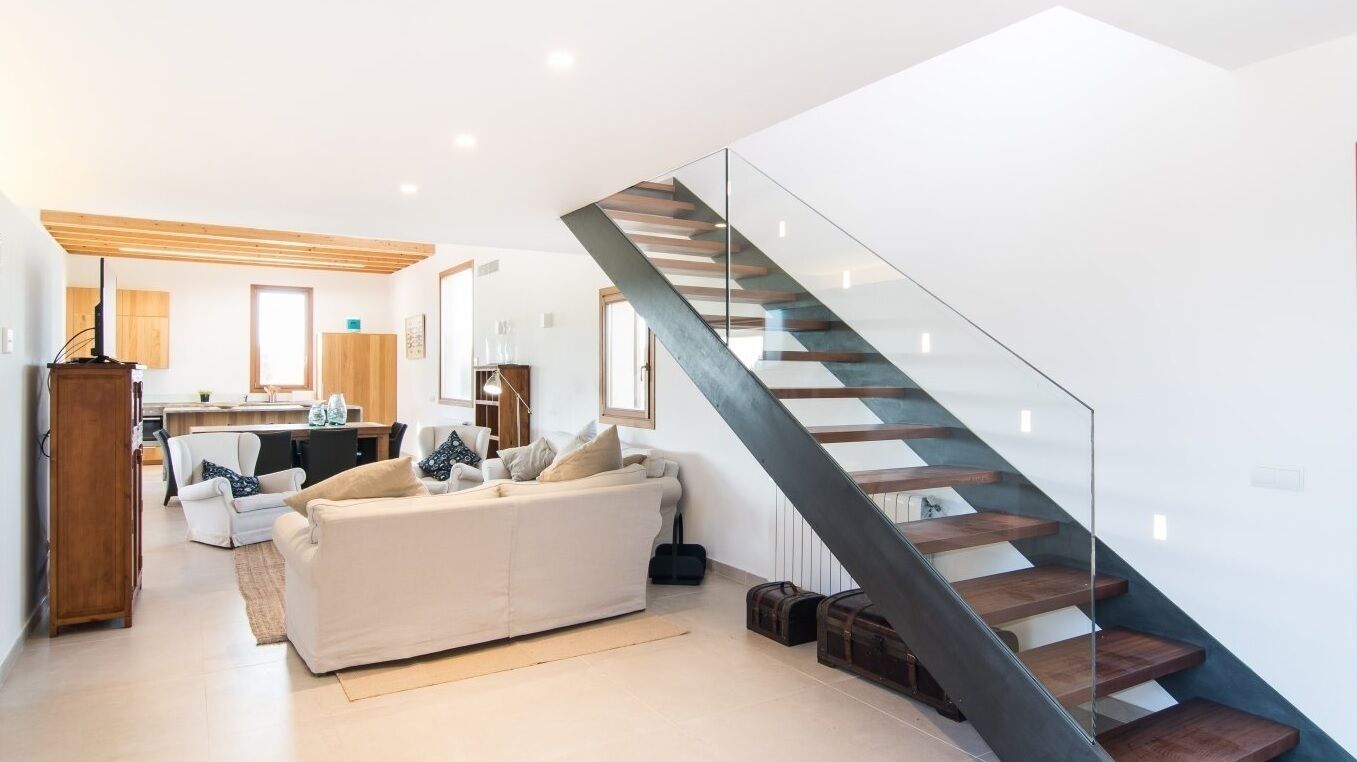 A modern living room with a staircase, a sofa, and a dining area.