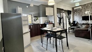 Een moderne keuken met een eethoek, witte kasten en een stenen muur.