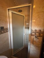 Un baño moderno con mampara de vidrio, zona de ducha y perchero.