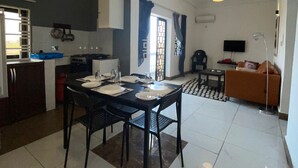 Een moderne keuken met een eethoek, met een grote tafel gedekt voor vier personen, een bank en een televisie in de woonkamer.