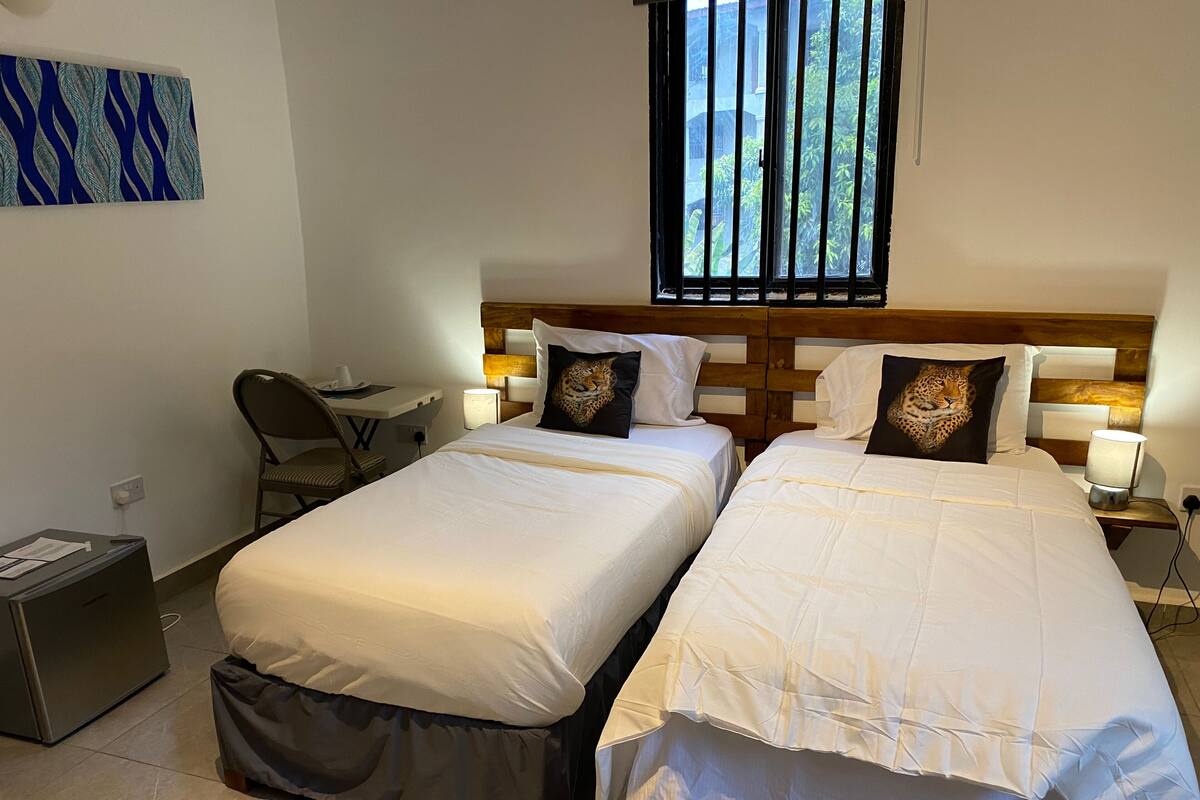 Een hotelkamer met twee bedden, een bureau en een stoel.
