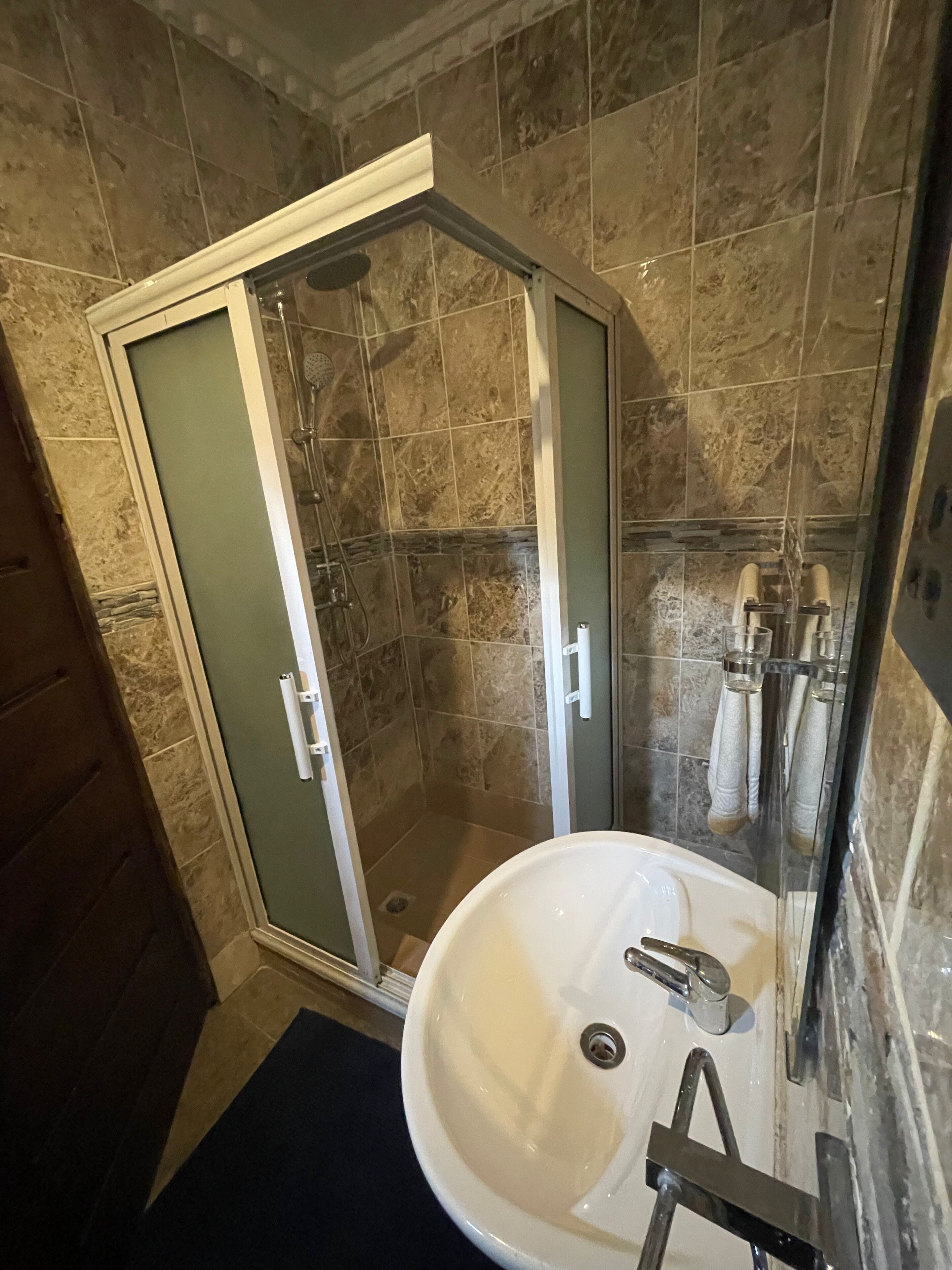 A bathroom with a glass-enclosed shower, a white sink, and a mirror.