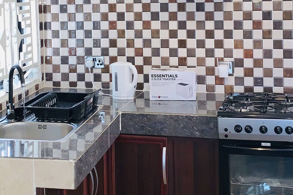 Een keuken met een zwart-wit geruit achterwand, een waterkoker, een broodrooster en een fornuis.