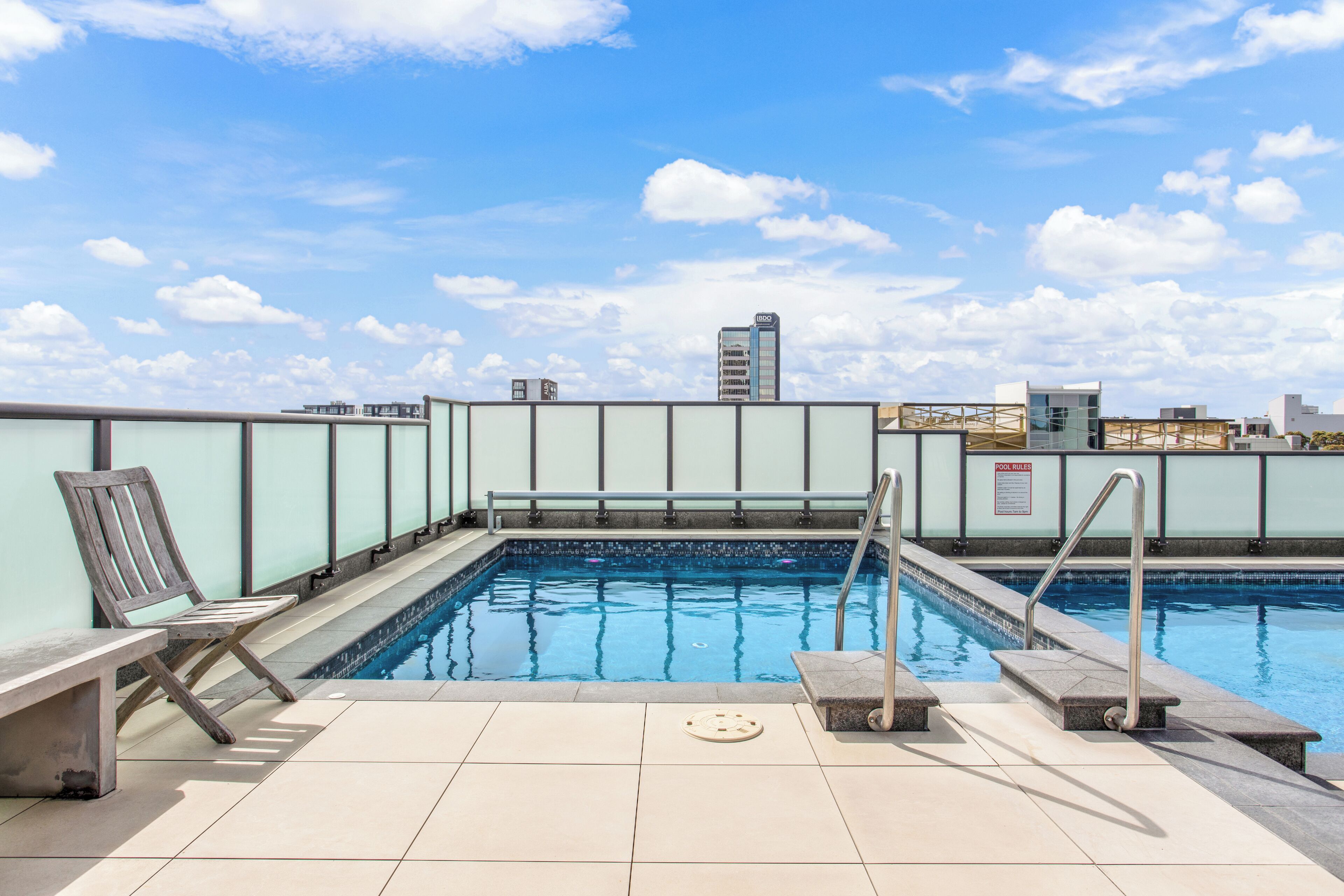 A rooftop pool with a view of the city skyline, including a tall building with 'IBDO' signage.