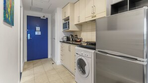Una cucina compatta con lavatrice, microonde e frigorifero in acciaio inossidabile.