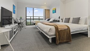 Una camera d'albergo moderna con un letto grande, una scrivania con televisore e vista sul mare.