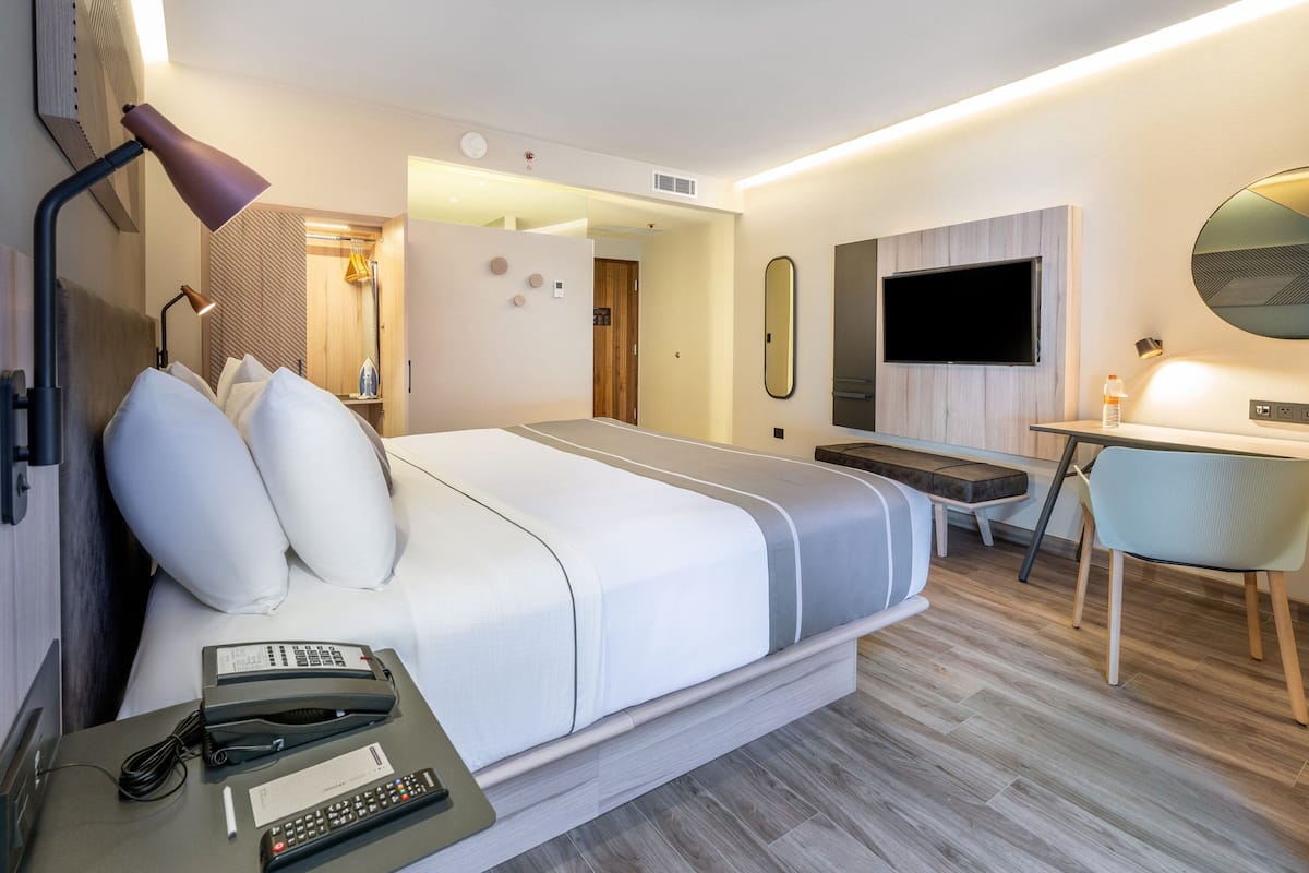 Une chambre d’hôtel moderne équipée d’un lit, d’une table de chevet, d’un bureau et d’une chaise.