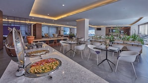 Un restaurante moderno con barra de mármol, sillas blancas y vistas a la ciudad.