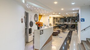 A modern hotel lobby with a reception desk, a staircase, and a seating area. - Hotel Wess Bogota (Bogotá)