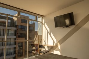 A modern room with a large window, a flat-screen TV mounted on the wall, and a small table with chairs. - Hotel Wess Bogota (Bogotá)