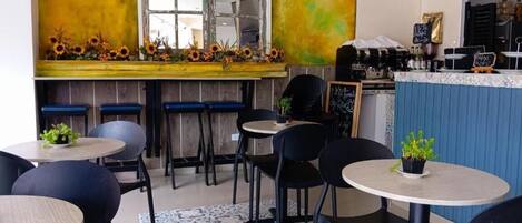 A cafe with a bar area, multiple tables and chairs, and a patterned floor.