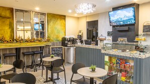 A modern bar area with a vintage mirror, a television, and a variety of snacks and beverages. - Hotel Wess Bogota (Bogotá)