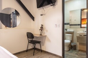 Un baño con inodoro, lavabo, espejo y una pequeña estatua en un estante.