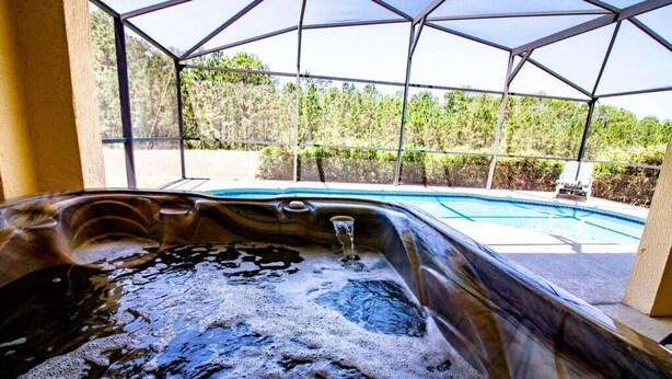 A hot tub with a transparent roof, surrounded by a pool and a view of a forested area. - 3 Bedroom, 2 Bath Tuscan Villa Vacation! (Davenport)