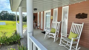 A covered porch with white rocking chairs and a sign reading 'Hairstyles by Jan.'