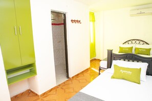 A hotel room with a bed, a green wardrobe, a door, and a wall-mounted air conditioner. - Ayenda 1609 Hotel Arrecife Caribeño (Santa Marta)