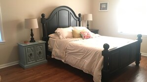 Un dormitorio con cama, mesitas de noche y ventana.
