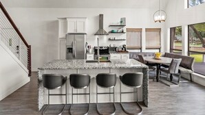 Une cuisine moderne dotée d’un îlot central, de tabourets de bar et d’un coin repas comprenant un canapé et une table.