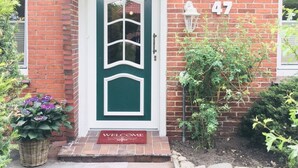 A brick house with a green door, a welcome mat, and a number 47 sign. - Restored Gulfhof in the heart of East Frisia (Ihlow)