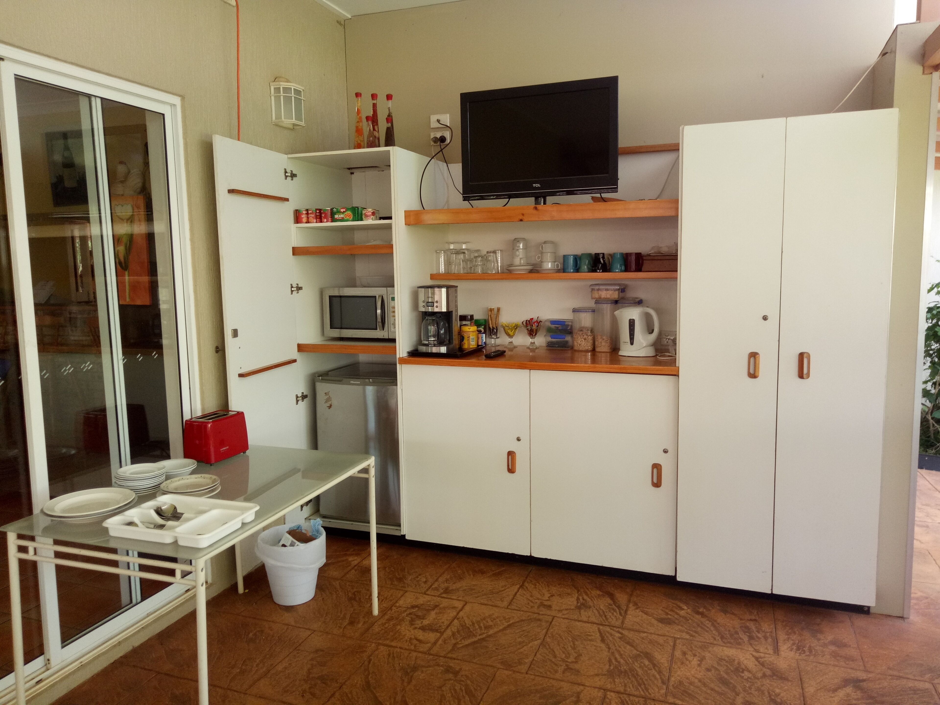 A compact kitchen with a microwave, coffee maker, and a TV on a shelf.