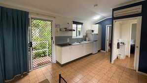Cocina compacta con puerta corrediza de vidrio que da a un balcón, microondas, refrigerador y un lavamanos.
