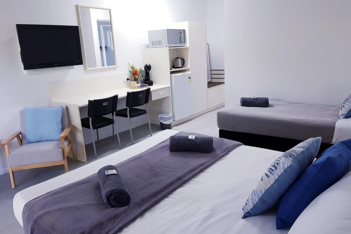 Une chambre d’hôtel avec deux lits, un bureau, une chaise, un four à micro-ondes et un réfrigérateur.