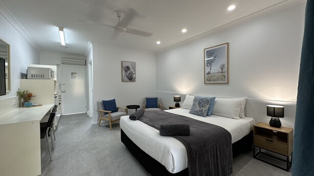 Un dormitorio moderno con cama, mesitas de noche, un escritorio y sillas.