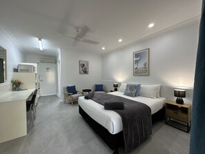 A modern bedroom with a bed, bedside tables, a desk, and chairs. - Mareeba Motor Inn (Mareeba)
