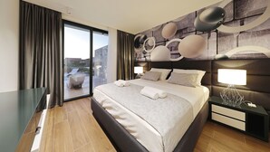 Une chambre moderne dotée d’un grand lit, d’une cloison en verre, d’une vue sur l’extérieur et d’un décor mural original.