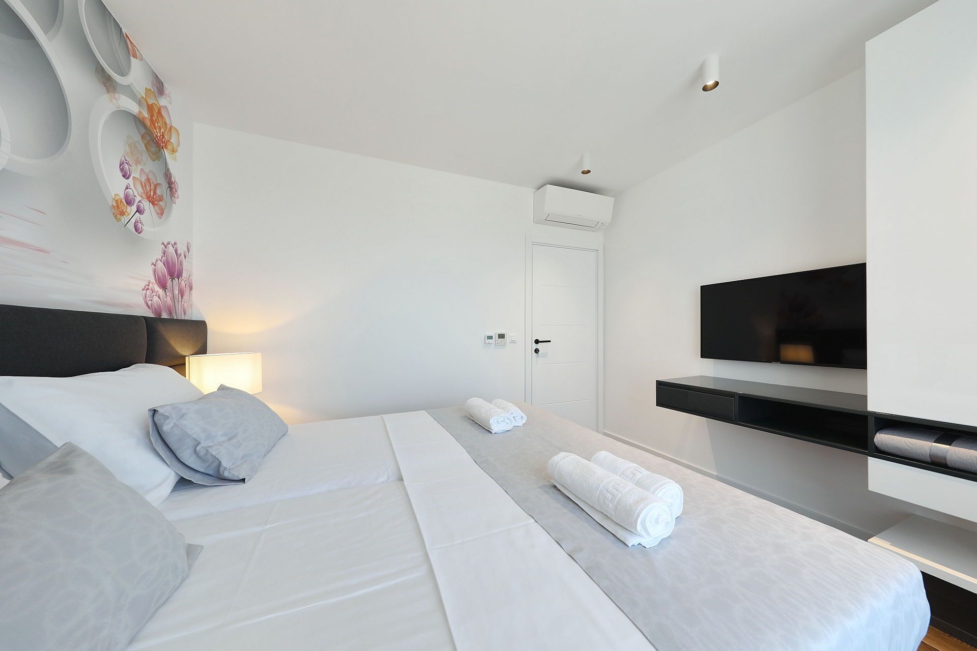 A modern hotel room with a large bed, a flat-screen TV, and a minimalist design.