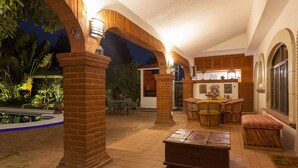 An outdoor patio area with brick pillars, a pool, and a seating area with wicker furniture. - Residencia Jardin Real (Cuernavaca)