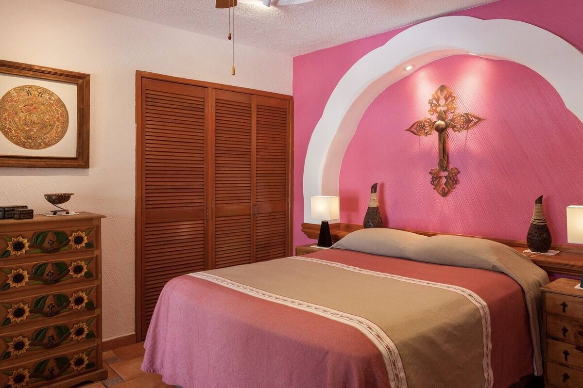 Un dormitorio con cama, armario de madera y una pared con arco decorativo.