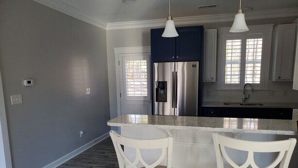 A modern kitchen with a central island, stainless steel appliances, and a window with blinds.