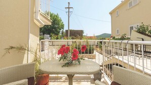 Ein Balkon mit Korbmöbeln, einem Tisch mit Blumen und Blick auf die umliegenden Gebäude und Grünflächen.